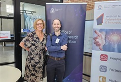 Two researchers standing in front of and OMRI banner and a FHRI banner at the FHRI Fund Open day